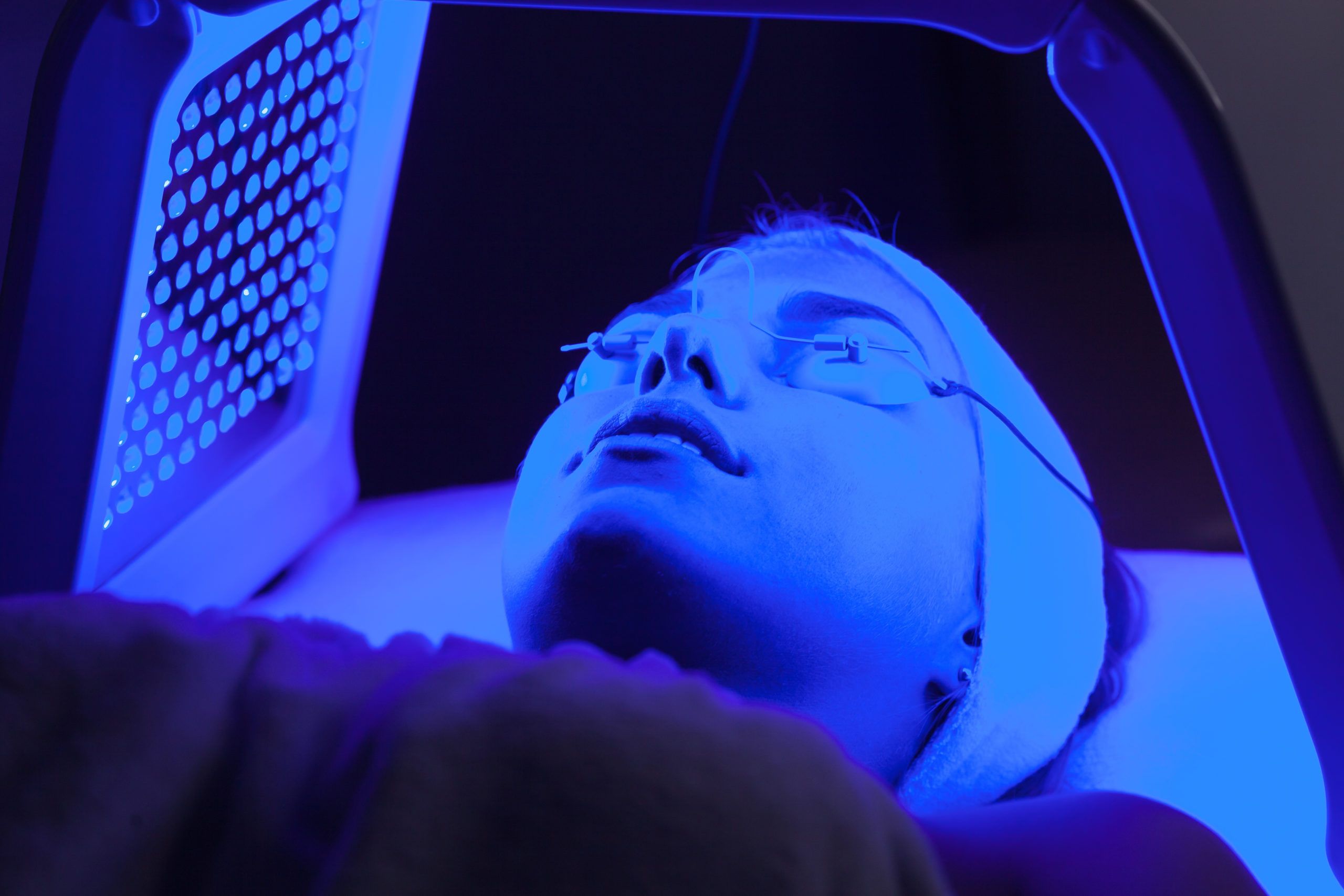 Young woman having LED light facial treatment in beauty salon